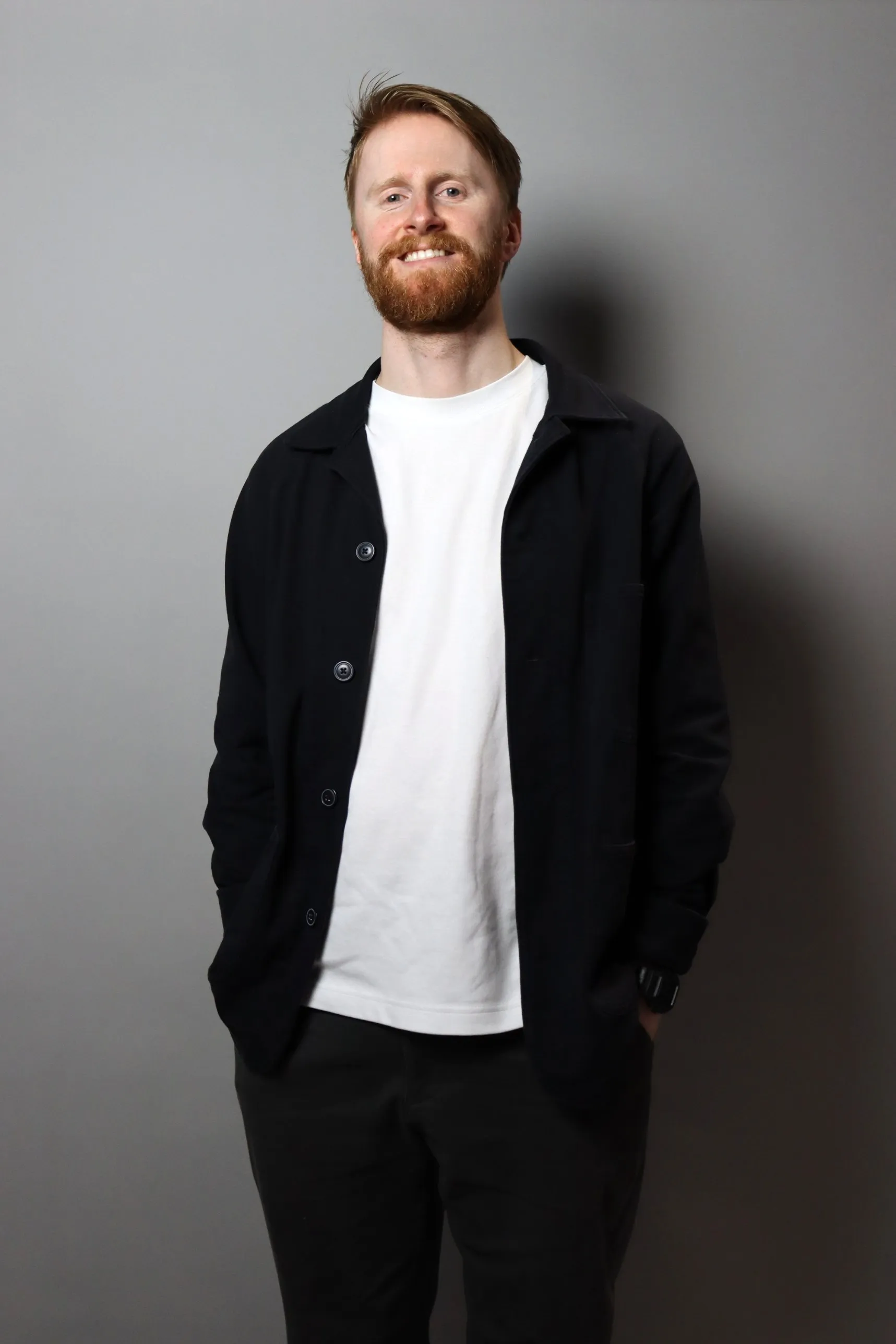 Chris Bullen, founder of Paramake, smiling in a dark work jacket and white t-shirt against a grey wall